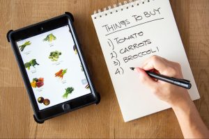 Grocery shopping list for meal prep with fresh vegetables and grains